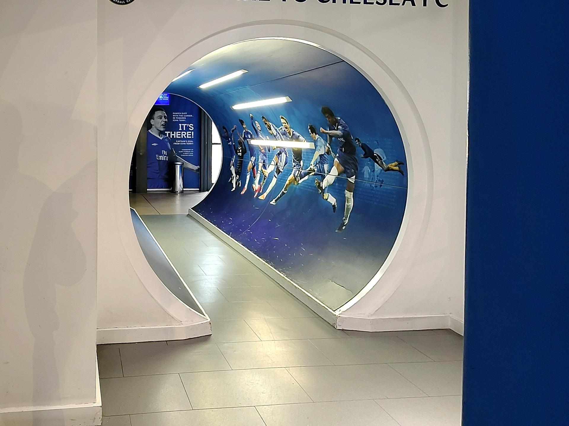 Dekoracyjne przejście przy wejściu do Chelsea FC z grafiką świętujących zawodników