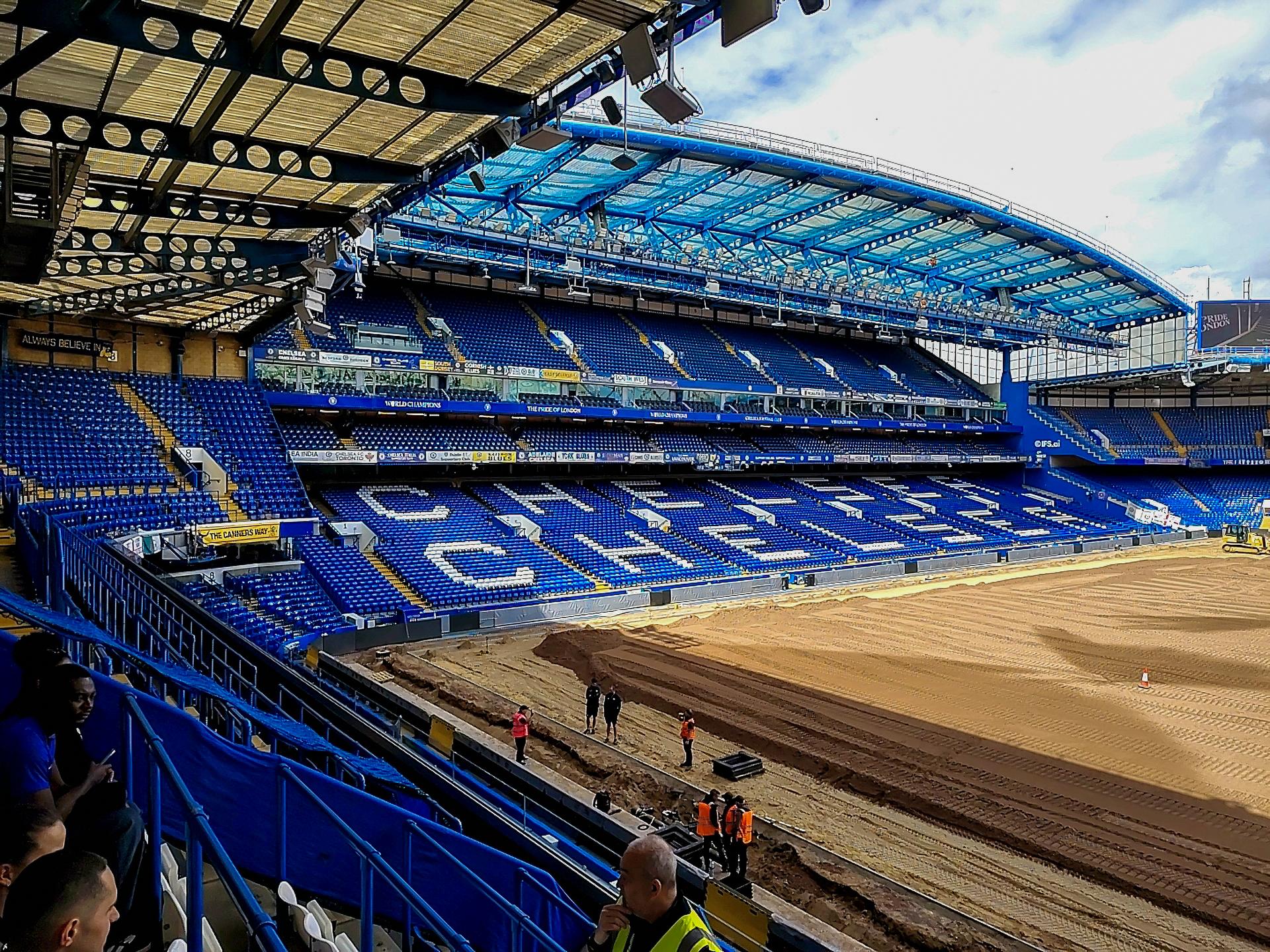 Grupa zwiedzających na trybunie Stamford Bridge z widokiem na płytę boiska