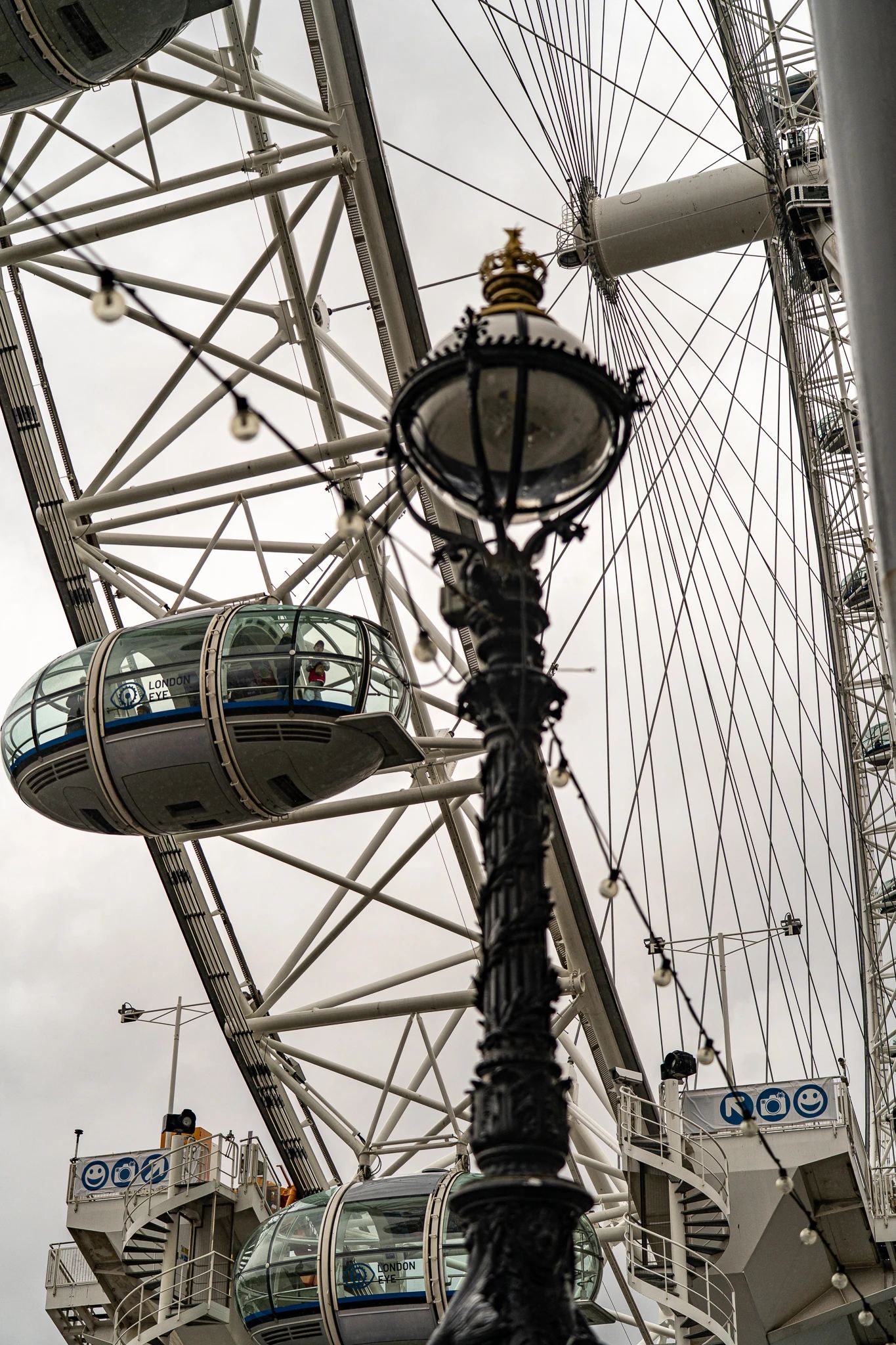 Kapsuły diabelskiego młyna London Eye widziane zza zabytkowej, ozdobnej latarni ulicznej w Londynie