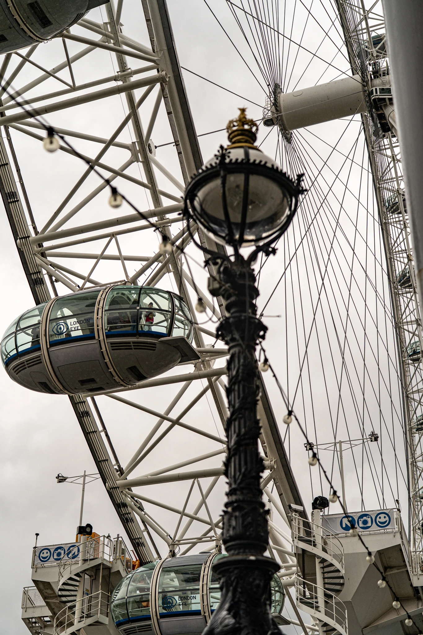 Kapsuły diabelskiego młyna London Eye widziane zza zabytkowej, ozdobnej latarni ulicznej w Londynie
