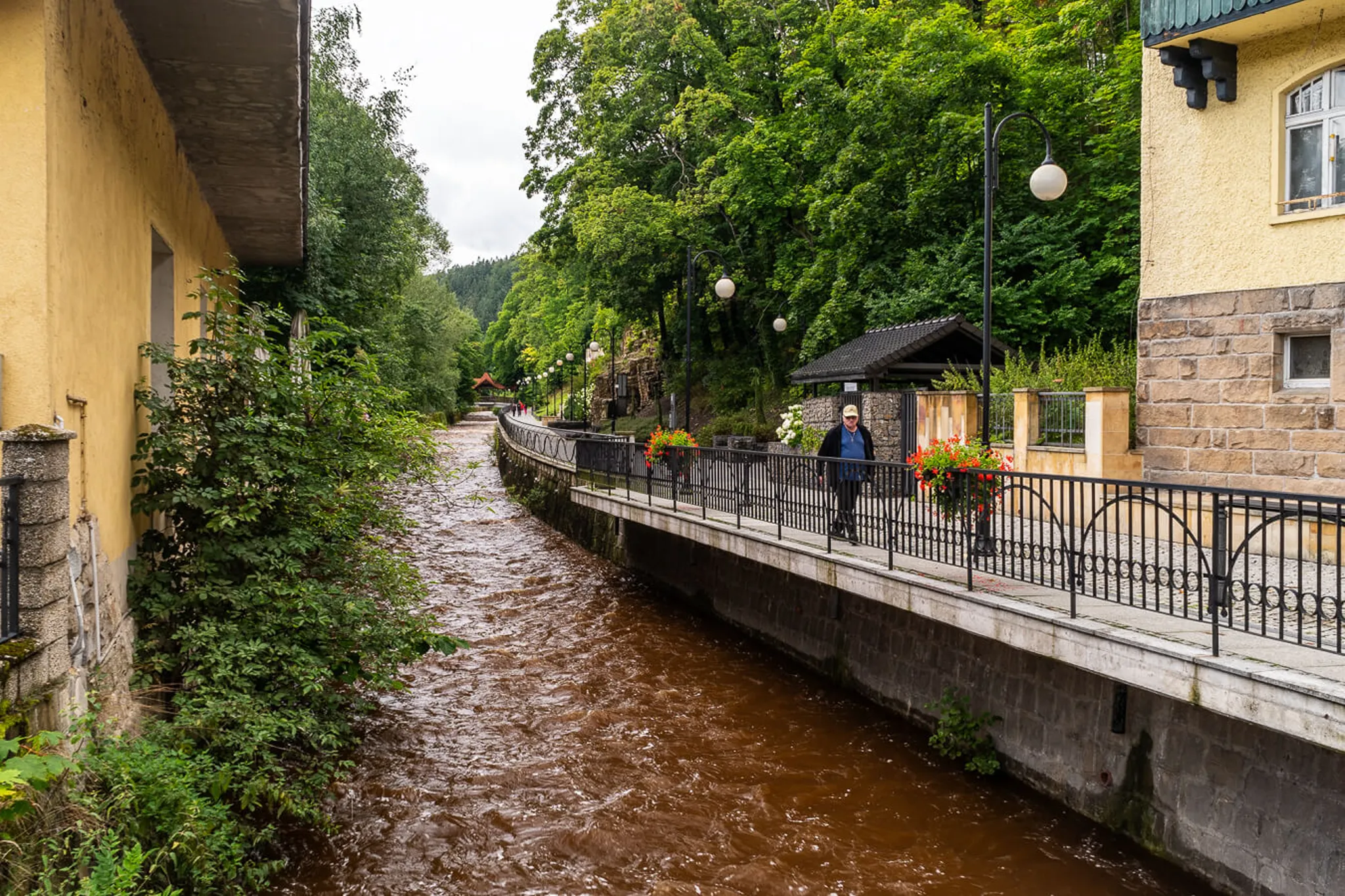 Zabytkowa tarasowa willa na wzgórzu w Polanicy Zdrój z czerwonymi kwiatami na balustradach i schodami terenowymi